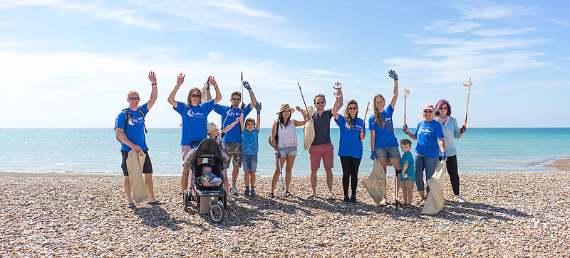 Mehrere Menschen des Big Blue Ocean Cleanup sind zu einem Gruppenfoto am Strand aufgestellt.