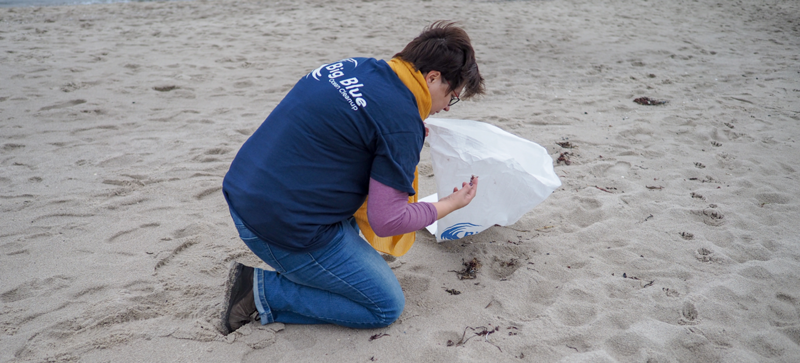 Eine Frau am Strand mit einem Müllsack