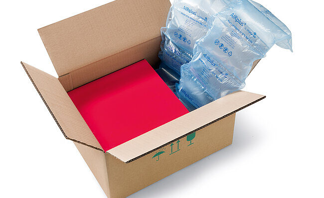 Ein Karton mit einer roten Box und Recycle Luftpolstern