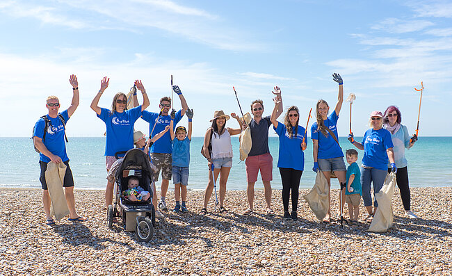 Mehrere Menschen des Big Blue Ocean Cleanup sind zu einem Gruppenfoto am Strand aufgestellt.